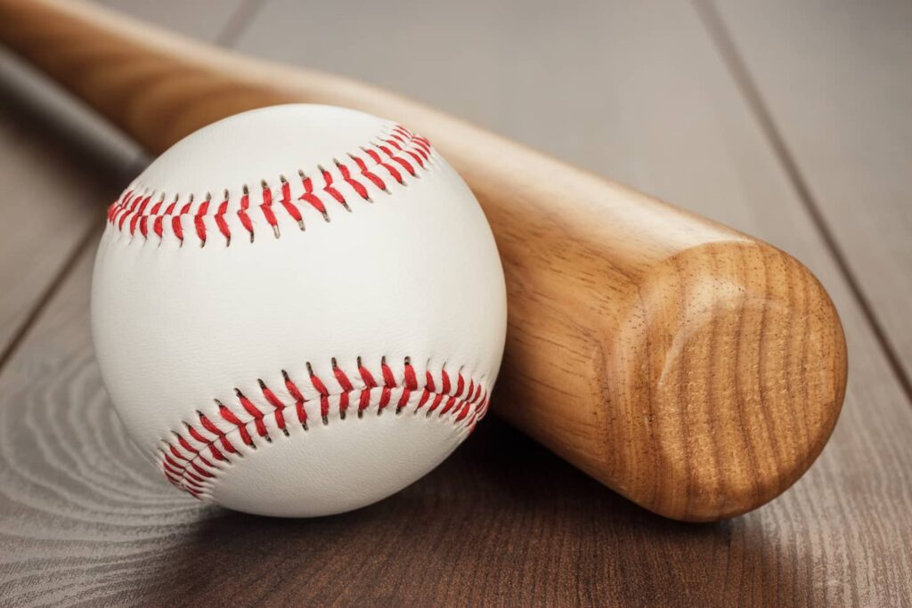 An image of a baseball bat and ball on wooden table.