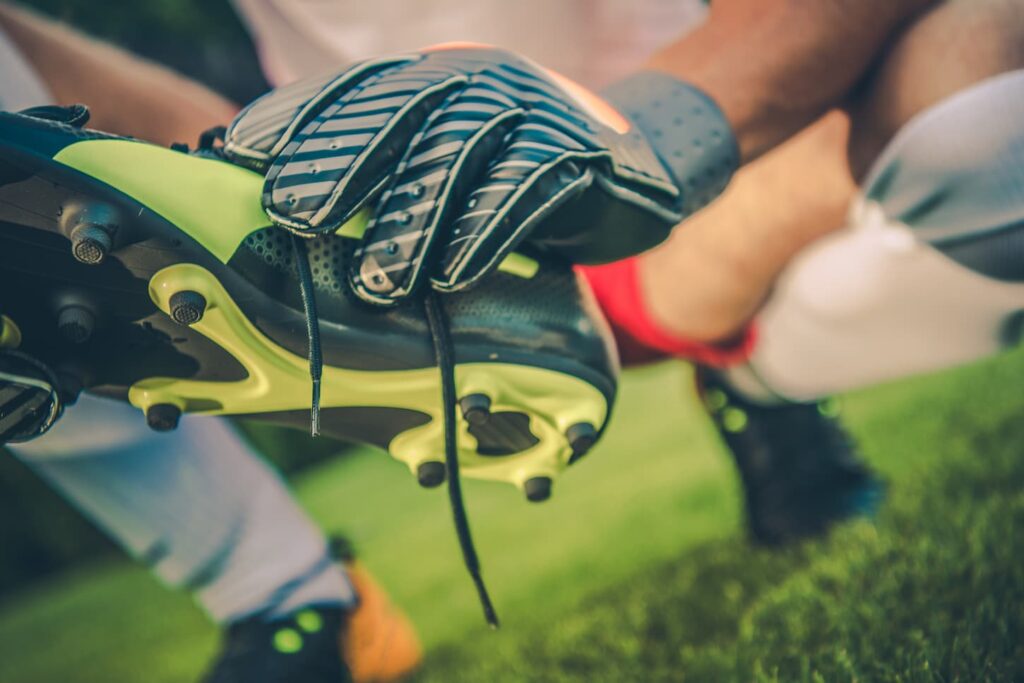 An image of a Soccer Goal Keeper Preparing For a Match. Football Cleats and Gloves Close Up.