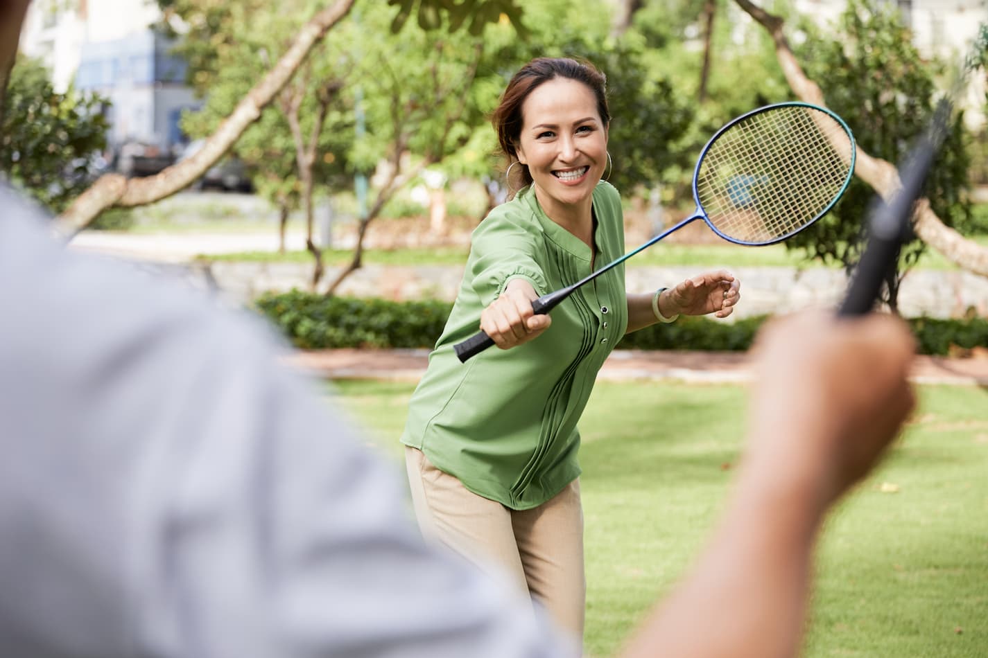 An image of a woman enjoying a game of badminton outdoors.
