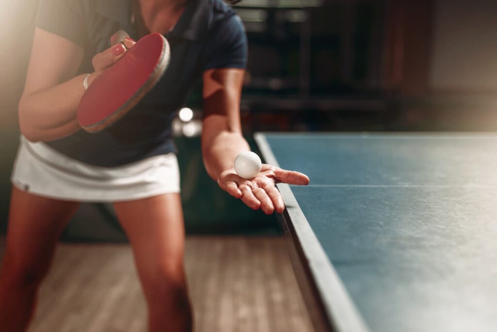An image of a Table tennis female player with a racket and ball.