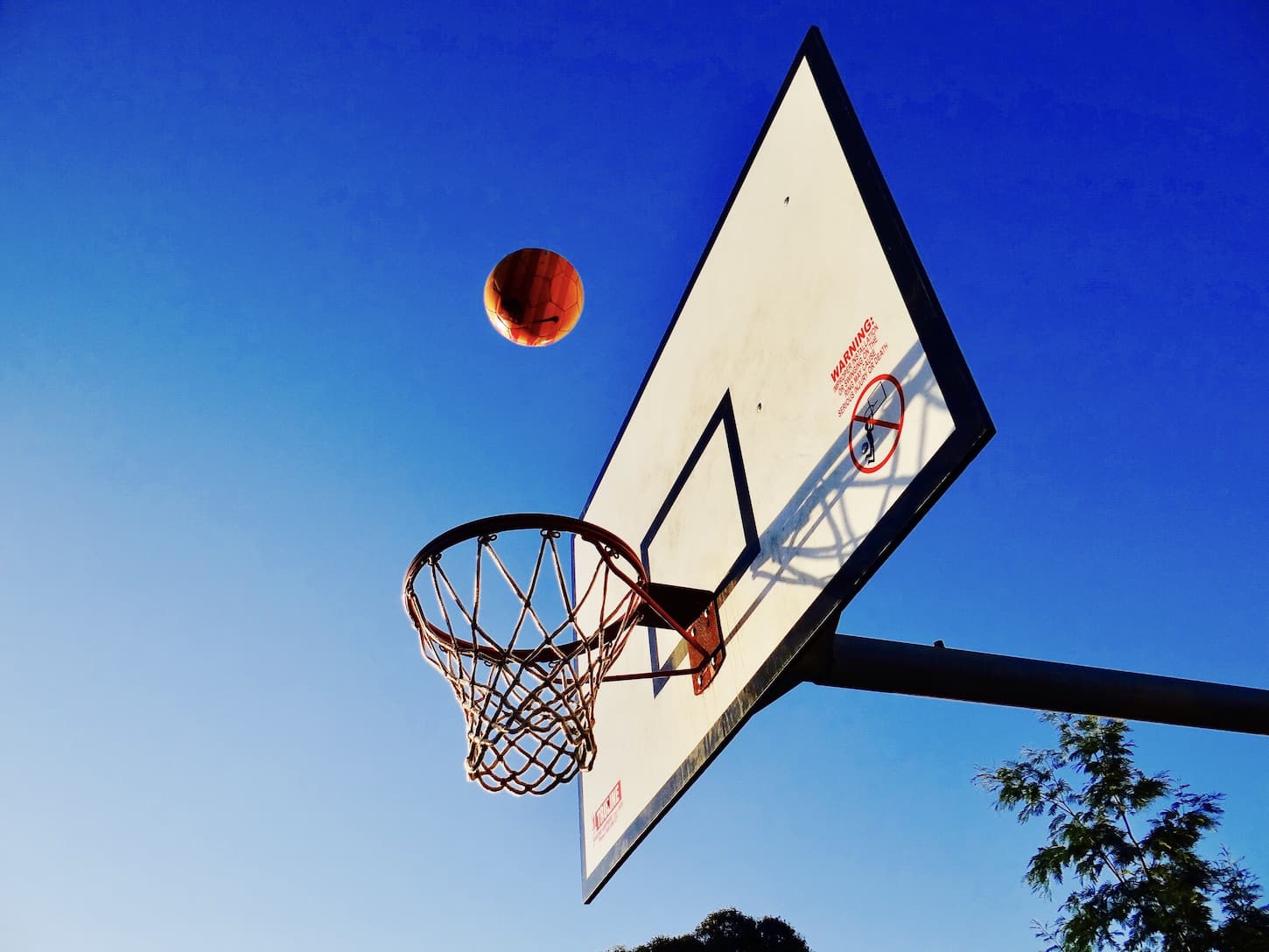 An image of basketball ring and a basket ball in a court.