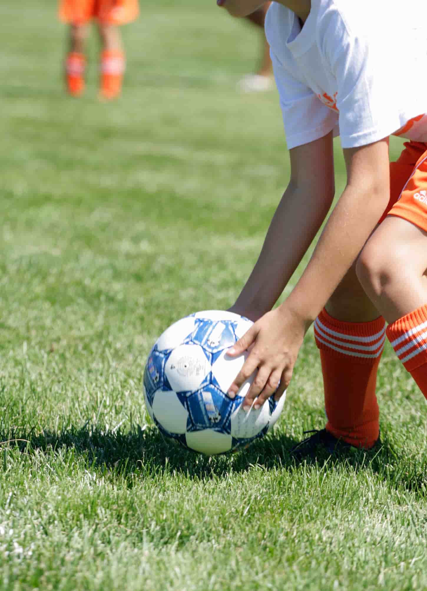 An image of a toddler on the field holding a soccer ball.