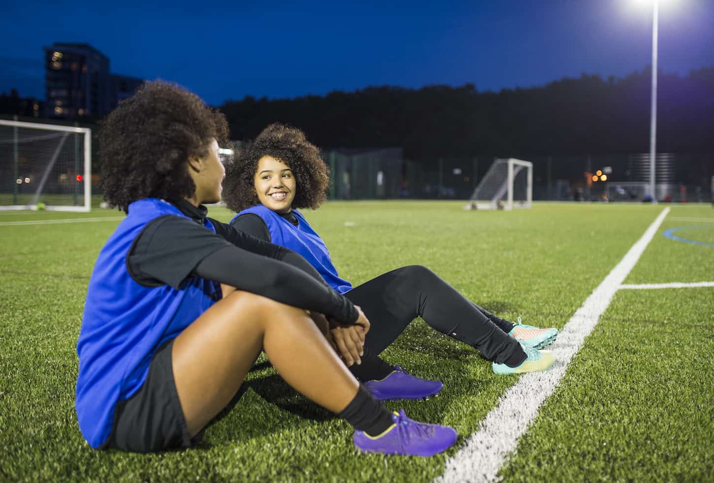 An image of Female football players sitting by the field, Hackney, East London, UK.