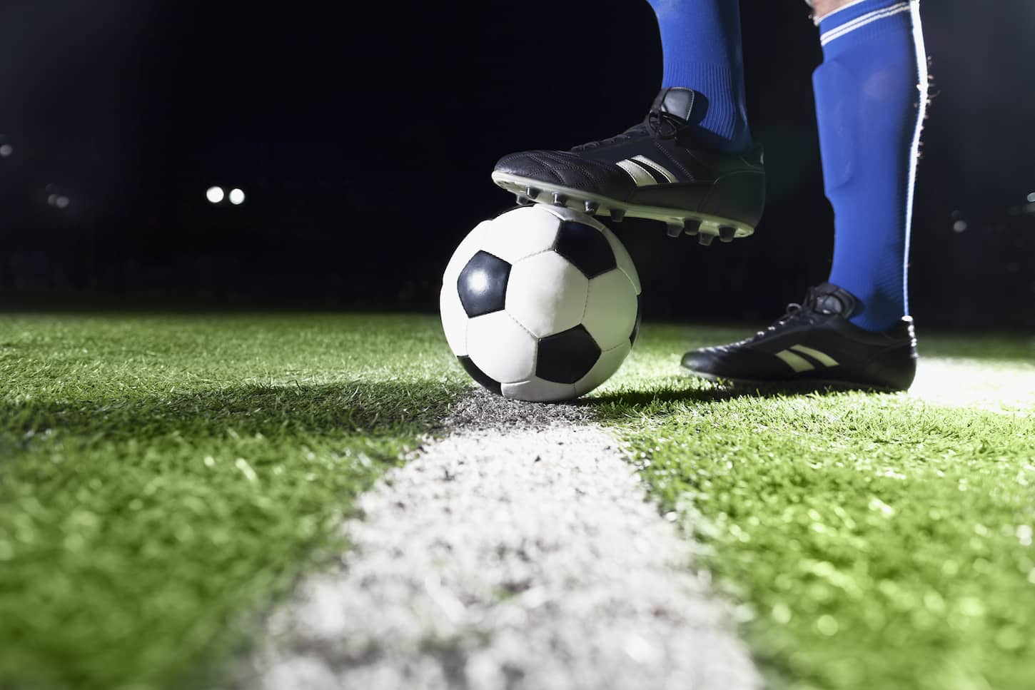 An image of a Foot on a soccer ball on the field.