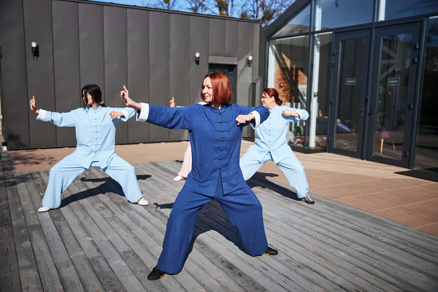 An image of Beautiful young women wearing colorful Chinese clothes practicing tai chi outdoors on a sunny day.