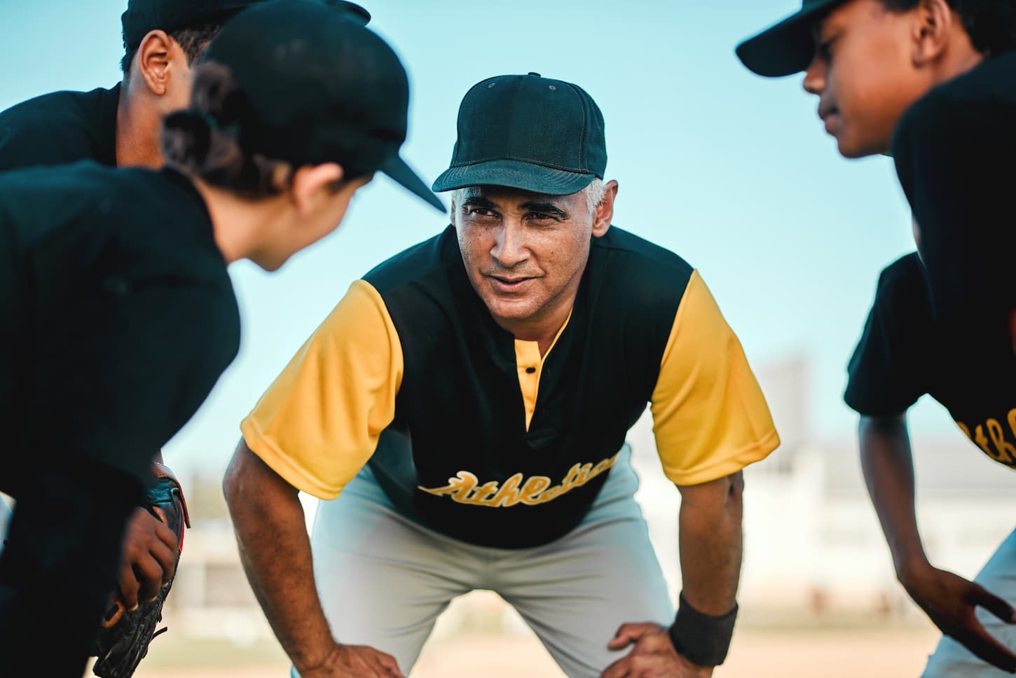 An image of a baseball coach talking to his team while out on the pitch.