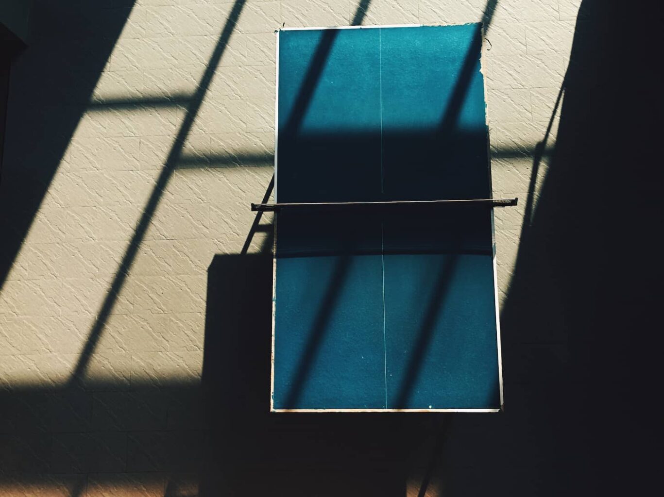 An image of a table tennis table in a room well lit with shadow from outside.