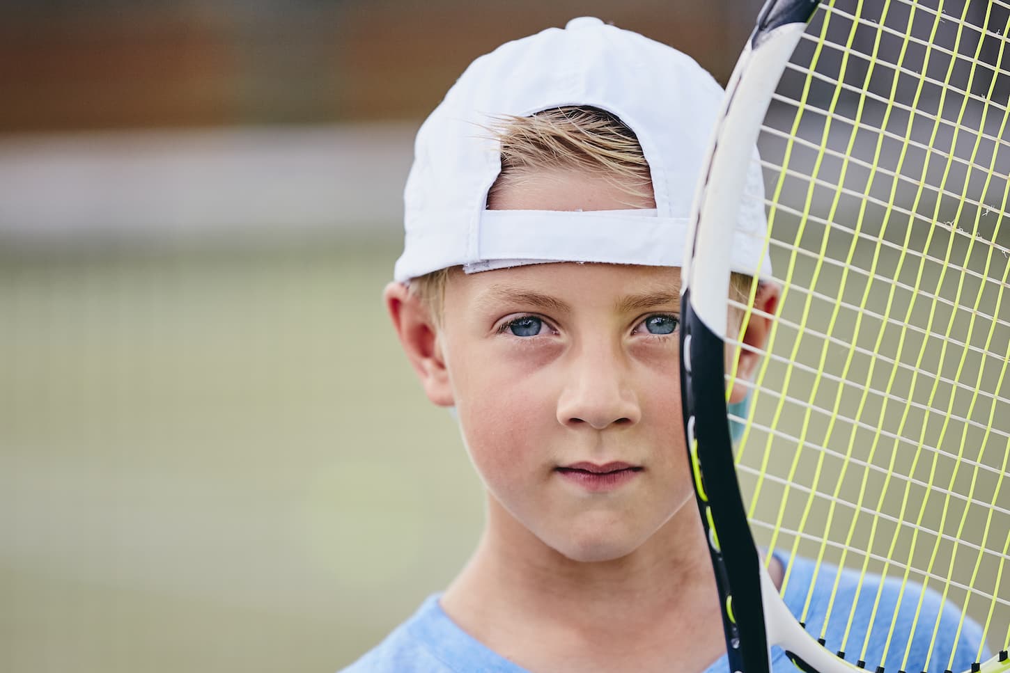 An image of a little boy holding a tennis racket on the court.