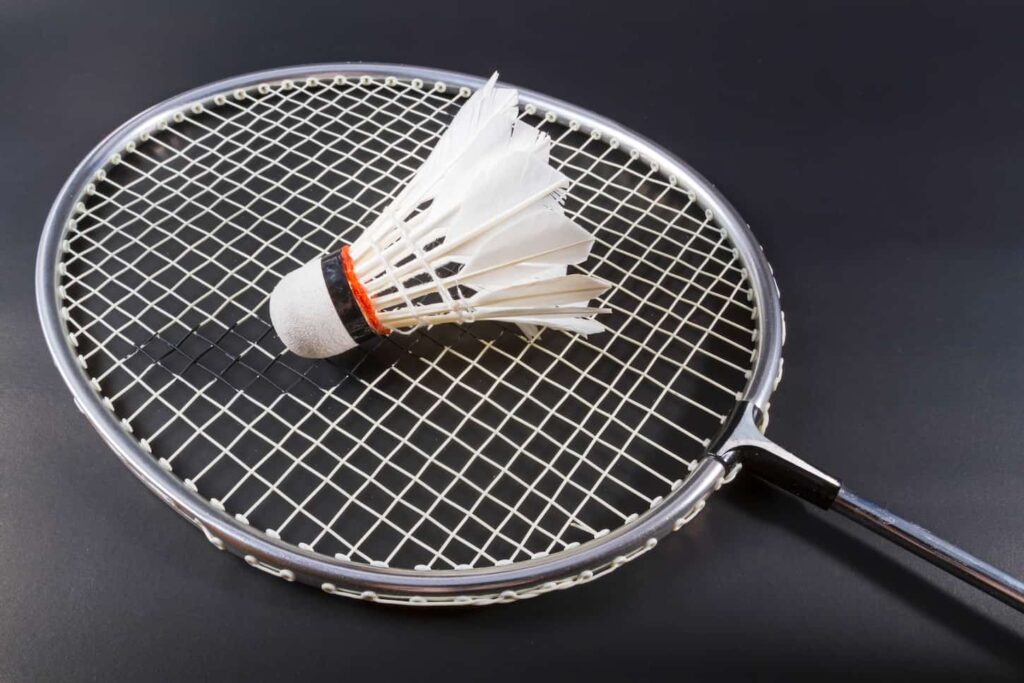An image of a Shuttlecock and badminton racket on dark background.