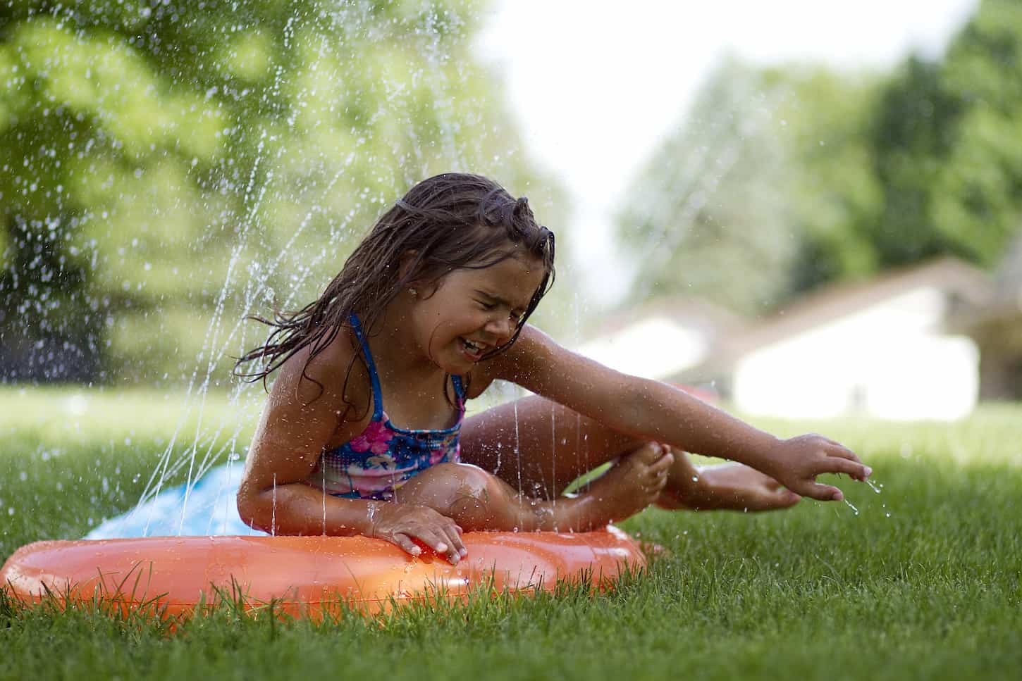 An image of a girl Sliding on a slip and slide outside, kids being kids, water and movement.