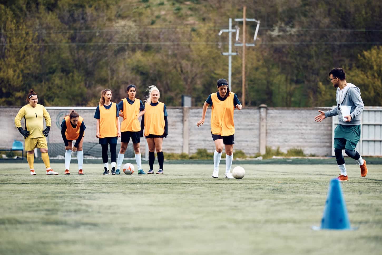 An image of a Soccer coach and female players during sports training on the playing field.