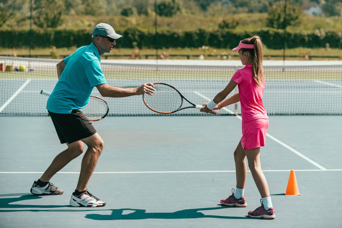 An image of a Tennis instructor with a young girl on tennis training.