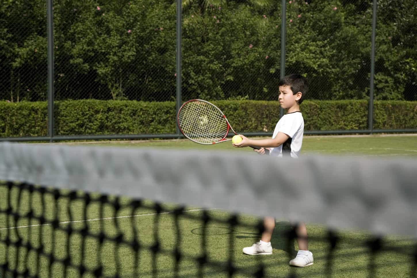 An image of a Young Chinese boy playing tennis.