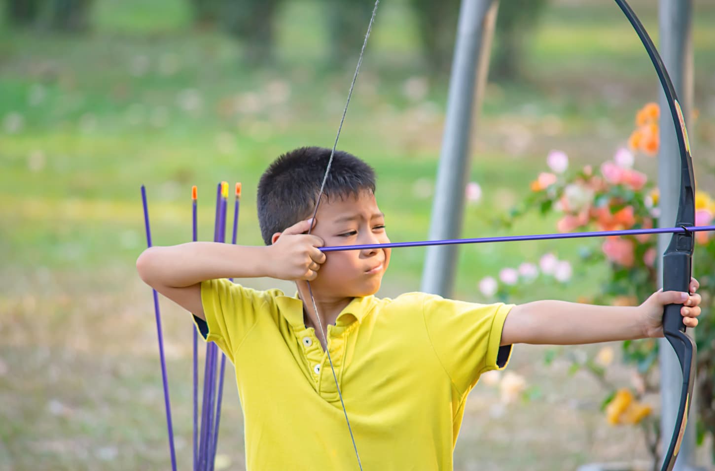 An image of an Asian boy doing archery in camp adventure.