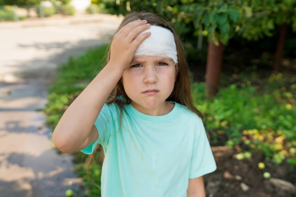 An image of a preschool girl with bandaged head after falling, hitting.