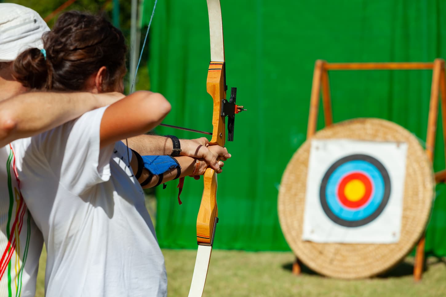 An image of a teacher teaching a student to aim at the goal. Archery course.
