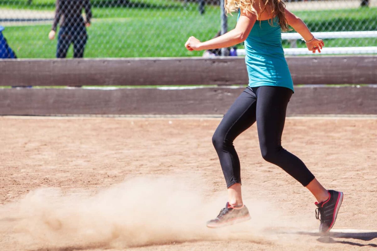 An image of a Woman Playing a Game of Kickball on the field.