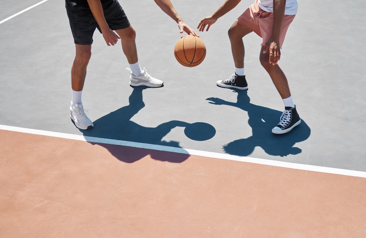 An image of two basketball players practicing and training basketball on an outside court.