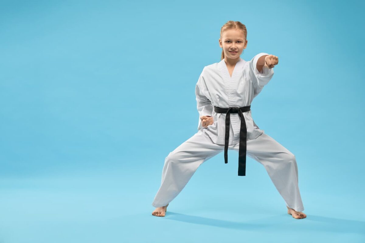 An image of a Female teenager standing in stance and exercising karate in a studio.