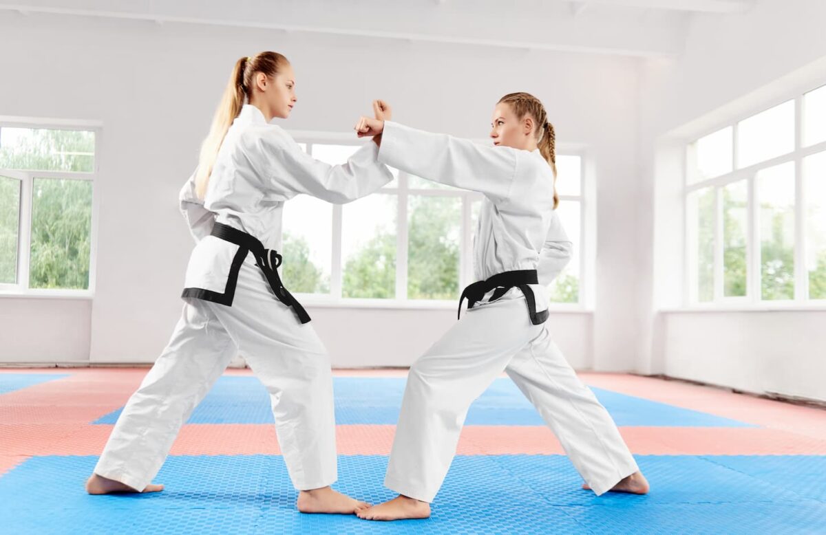 An image of Two athletic girls struggling to use karate techniques in light karate class.