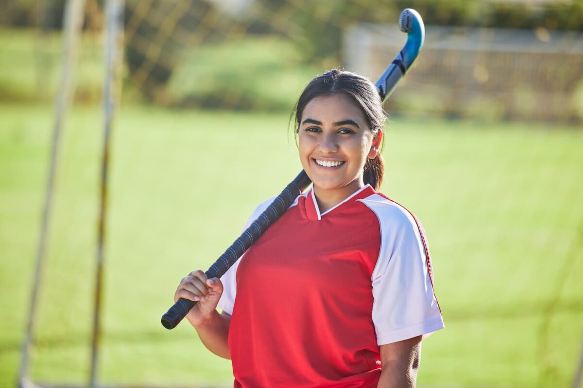 An image of a Happy female hockey coach portrait, a women's team sport played with a natural field background outdoors.